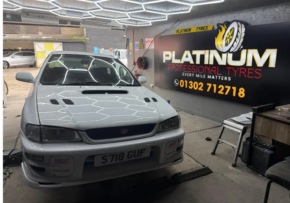 Subaru in the Platinum Professional Tyres workshop with branded wall signage